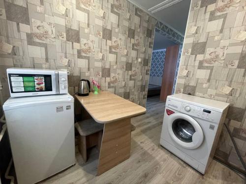 una pequeña cocina con lavadora y mesa en Отличная 1-комнатная квартира в центре! Standart, en Petropavlovsk