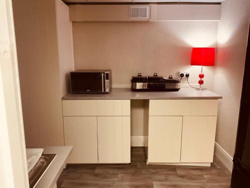 a kitchen with a microwave and a red lamp on a counter at The Danescourt in Blackpool