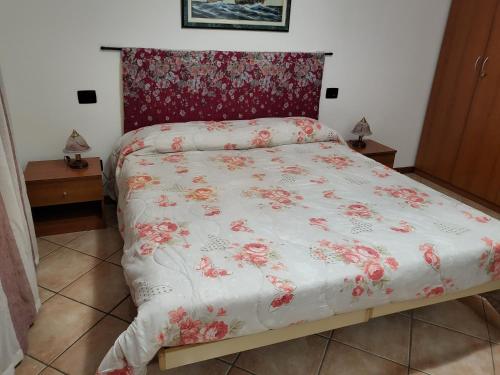 a bed with a white comforter with red flowers on it at Dantino in Novara