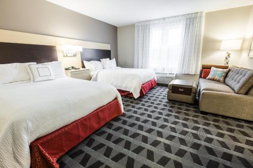 a hotel room with two beds and a couch at TownePlace Suites by Marriott Gilford in Gilford