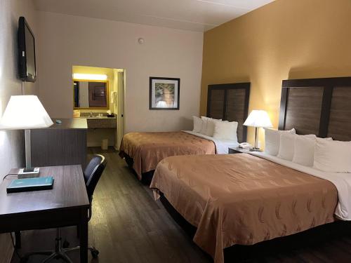 a hotel room with two beds and a desk at Quality Inn in Maysville