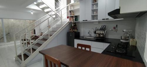 una cocina con una mesa de madera y una escalera en Rumah Bahagia 36 en Bonorejo