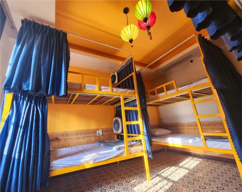 two bunk beds in a dorm room with blue curtains at iHome Hoi An in Hoi An