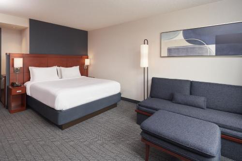 a hotel room with a bed and a couch at Courtyard by Marriott Glassboro Rowan University in Glassboro