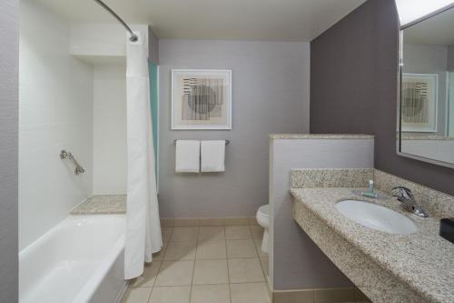 a bathroom with a tub and a sink and a toilet at Courtyard by Marriott Glassboro Rowan University in Glassboro