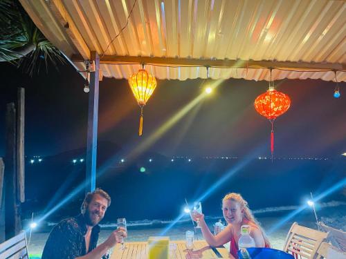 a man and woman sitting at a table with wine glasses at Bãi Xếp Beach in Quy Nhon