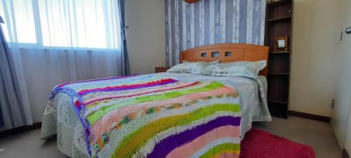 ein Schlafzimmer mit einem farbenfrohen Bett mit einer bunten Decke in der Unterkunft Depto Valparaiso in Temuco