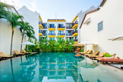 a swimming pool with chairs and a building at Silkotel Hoi An in Hoi An