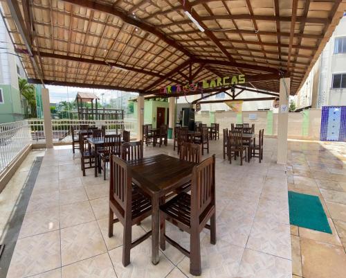 a restaurant with wooden tables and chairs under a roof at Apartamento na Grande Natal (Condomínio Barcas) in Natal