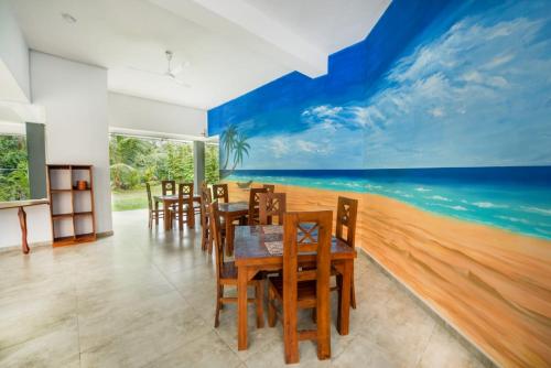 a dining room with a beach mural on the wall at Sol Y Mar - Unawatuna in Galle