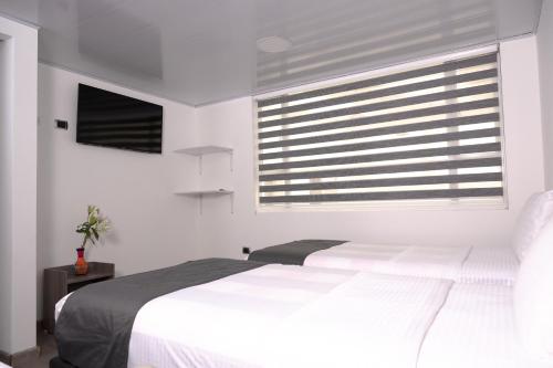 a white bedroom with a bed and a window at Hotel Montefiore in Bogotá