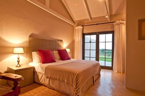 a bedroom with a bed with red pillows and a window at Country House at Kay & Monty in The Crags