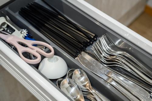 a drawer filled with silver utensils and a pair of scissors at Orange Line in Inbu