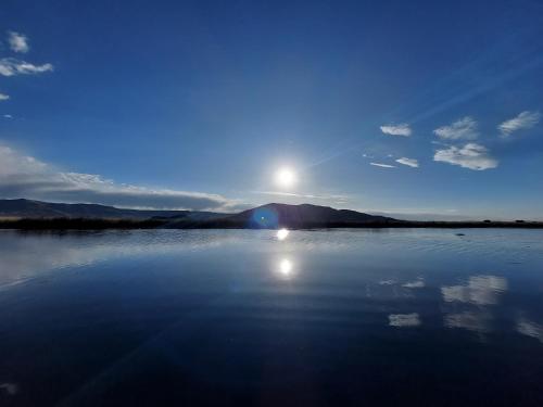a large body of water with the sun in the sky at Uros Lodge Perú in Puno