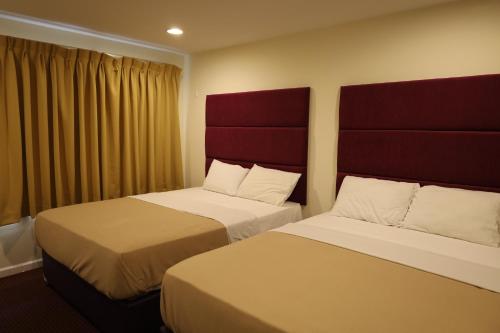 um quarto de hotel com duas camas e uma cabeceira vermelha em The Hamlet Inn at Warwick em Warwick