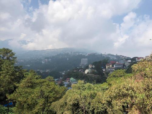 uitzicht op een stad vanaf een heuvel met bomen bij GH Apartelles in Baguio