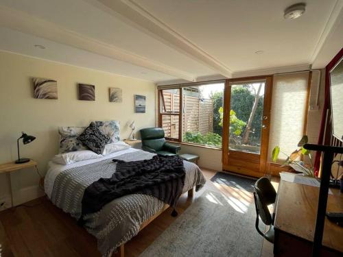 ein Schlafzimmer mit einem Bett und einem großen Fenster in der Unterkunft The Undercroft - Cosy boutique studio apartment. in Moonah