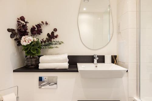 a white bathroom with a sink and a mirror at Wild Roses Serviced Apartments - Upton Park in London