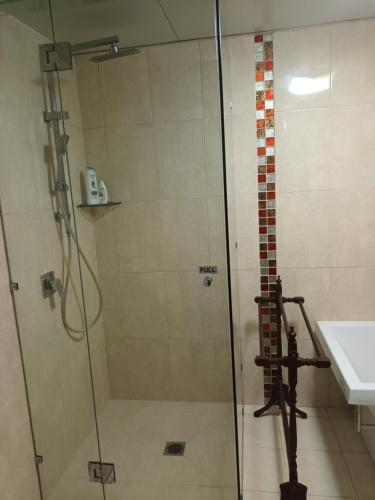 una ducha con una puerta de cristal junto a un lavabo en Tropical Poolside Retreat, en Nelly Bay