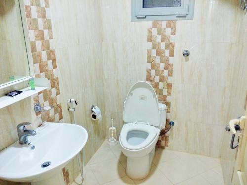a bathroom with a toilet and a sink at Hona Al Holm Furnished Units in Dammam