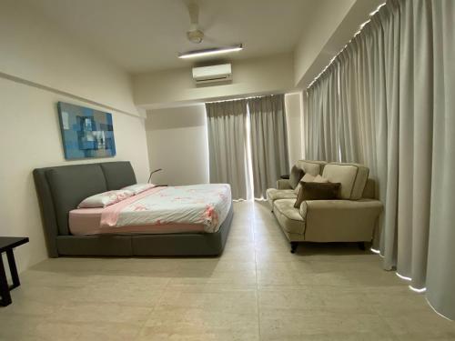 a bedroom with a bed and a couch and a chair at BY THE SEA - Penthouse 3 bedroom in Batu Ferringhi