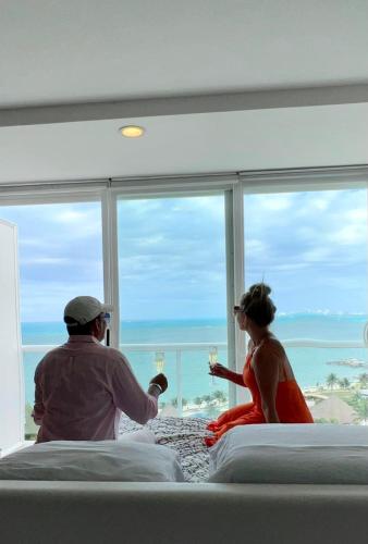カンクンにあるAmara Cancun Beachfront Condoのワインを飲みながらホテルの部屋に座っている男女