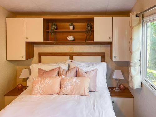 a bedroom with a bed with white sheets and pink pillows at Robins Retreat in Weybourne