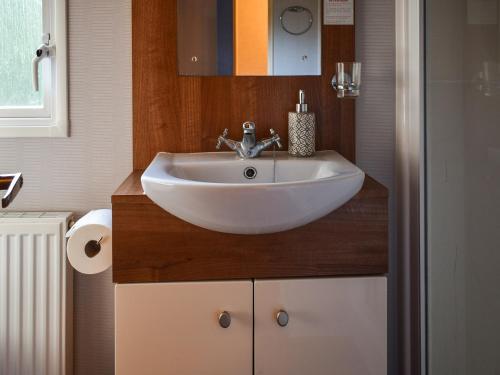 La salle de bains est pourvue d'un lavabo blanc et d'un miroir. dans l'établissement Robins Retreat, à Weybourne