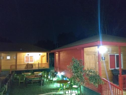 a house with a patio with tables and chairs at night at The Laughing Woods AC Resort in Kotagiri