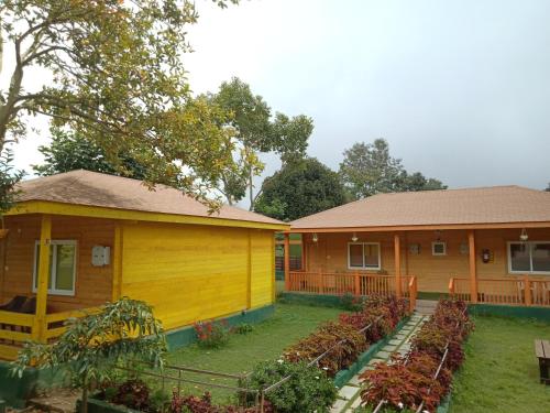 a yellow house with a garden in front of it at The Laughing Woods AC Resort in Kotagiri