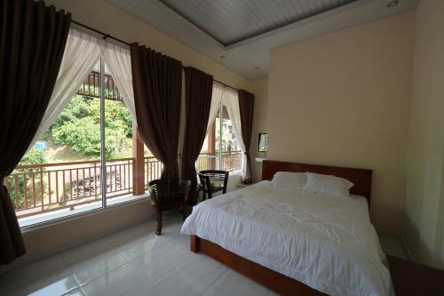 a bedroom with a bed and a balcony with windows at Ida Guest House & Restaurant in Bukit Lawang