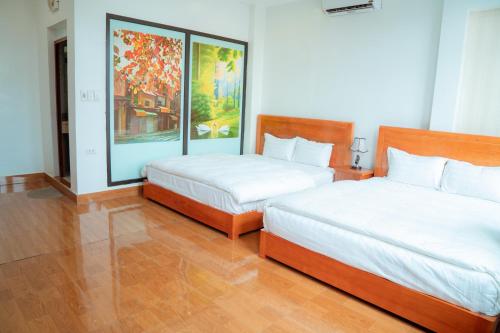 a bedroom with two beds and a painting on the wall at Luxury Airport Hotel & Travel in Noi Bai