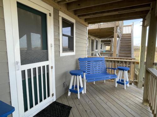 a blue bench on a porch with two stools at NC 12 56821-7 Condo in Hatteras