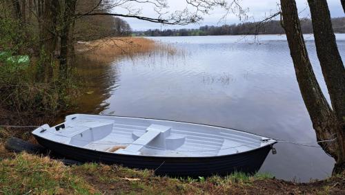 a white boat sitting on the side of a lake at Chatka Leo in Fornetka