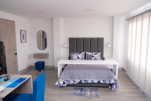 a bedroom with a bed and a blue chair at Aparta suite tequendama in Cali
