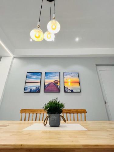 a dining room table with four pictures on the wall at Inn Homestay in Teluk Intan