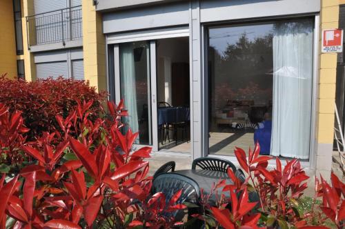 a patio with two chairs and a window with red plants at Camping Villaggio Paradiso in Domaso
