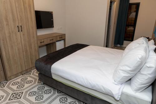 a bedroom with a white bed and a television at Saint Jacob Hotel in Nazareth