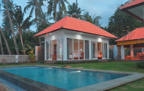 a house with a swimming pool and a red roof at Mojito Beach Villas in Kubutambahan