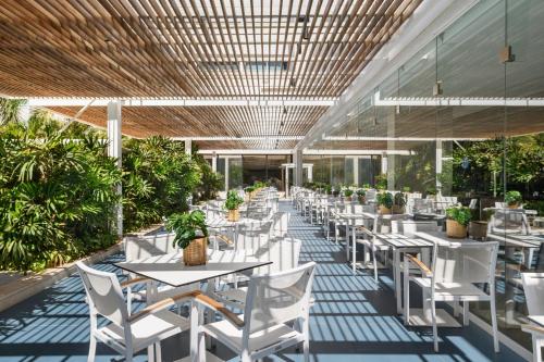 a restaurant with white tables and chairs and plants at Lagoona by Isrotel Collection in Eilat
