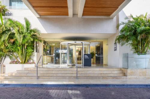a lobby of a building with stairs and palm trees at Lagoona by Isrotel Collection in Eilat
