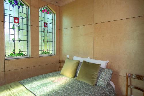 a bedroom with a bed and two stained glass windows at The Church Millers Flat in Millers Flat
