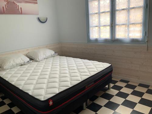 - un lit dans une chambre avec un sol en damier dans l'établissement Villa Magaly T3 à 50 m de la plage Valras centre, à Valras-Plage