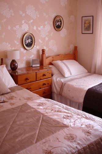a bedroom with two beds and a wooden dresser at Westview Accommodation in Stornoway
