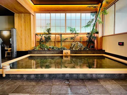 una piscina de agua en una habitación con ventana en かぷせる旅籠 赤坂 SPABLIC INN, en Tokio