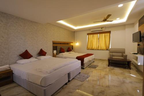a hotel room with two beds and a television at Hotel Woodside Prestige in Tirupati
