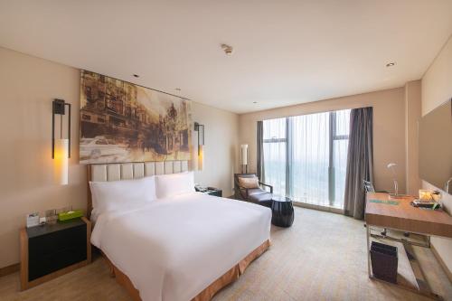 a hotel room with a large white bed and a desk at Junluxe Hotel Guangzhou Science City-Free Shuttle Bus Service to Guangzhou Canton Fair in Guangzhou