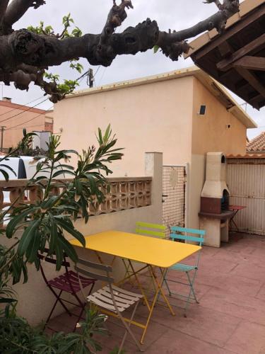 une table et des chaises jaunes sur une terrasse dans l'établissement Villa Magaly T3 à 50 m de la plage Valras centre, à Valras-Plage
