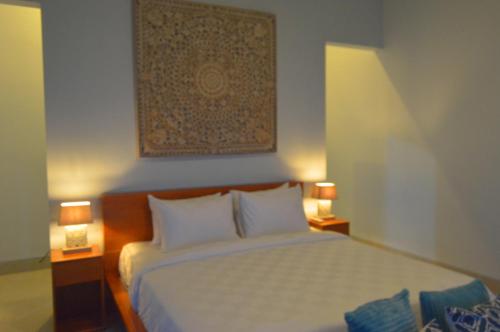 a bedroom with a large bed with two lamps at Mojito Beach Villas in Kubutambahan