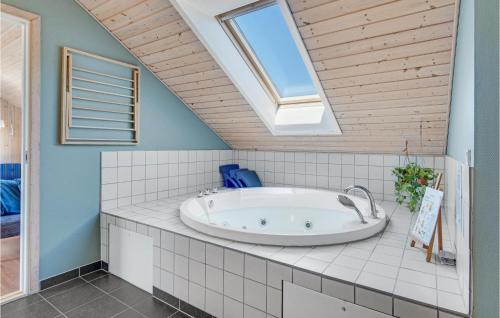 GrønhøjにあるNice Home In Lkken With 4 Bedrooms, Sauna And Wifiの天窓付きのバスルーム(バスタブ付)